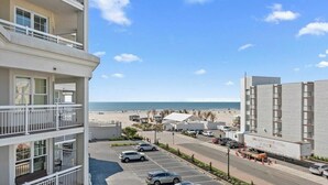 A multi-story hotel with balconies, a parking lot, and a view of the beach. - Residence 308 at The Grand (Wildwood)