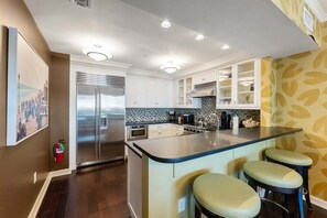 Una cocina moderna con una isla central, electrodomésticos de acero inoxidable y taburetes de bar.