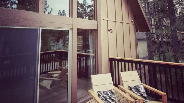 Een modern gebouw met grote ramen en een terras met twee loungestoelen.