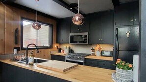Een moderne keuken met een houten aanrecht, roestvrijstalen apparatuur en hanglampen.