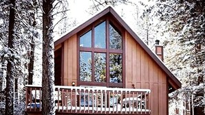 Een houten hut met een balkon, omgeven door met sneeuw bedekte bomen.