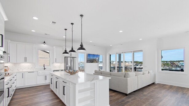 A modern kitchen with white cabinetry, a central island, and pendant lighting. - Carolina Blue Skies is 2nd Row, Steps to the Beach, Ocean Views and New Construction (Holden Beach)
