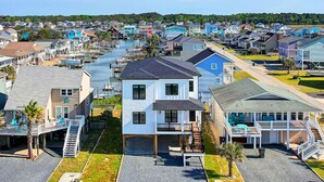 A coastal residential area with houses, a marina, and a clear view of the water. - Carolina Blue Skies is 2nd Row, Steps to the Beach, Ocean Views and New Construction (Holden Beach)