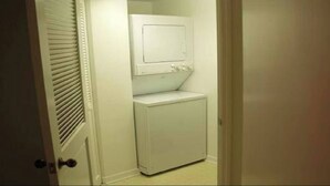 Un cuarto de lavado con lavadora y secadora, una puerta con picaporte y un interruptor de luz en la pared.