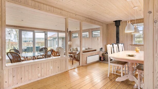 A wooden-paneled room with a dining table, chairs, and a bench.
