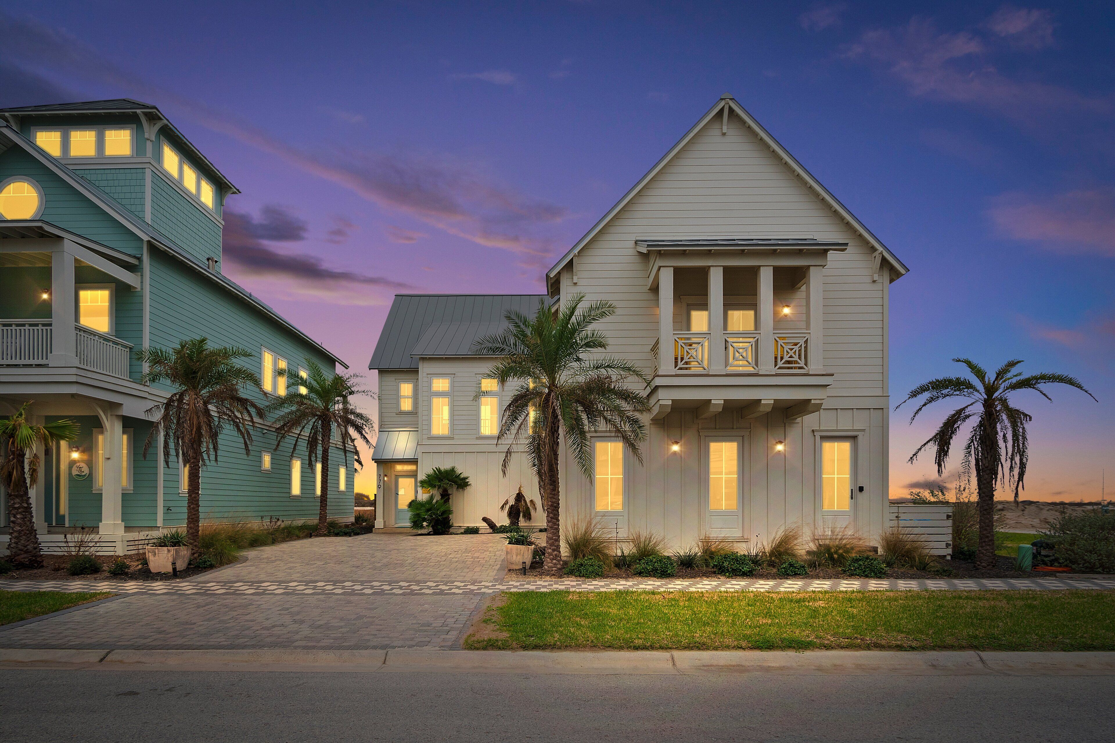 A two-story house with a front porch, a balcony, and a driveway leading to the entrance.
