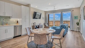 Una cocina moderna con gabinetes blancos, un comedor con mesa y sillas redondas, y un ventanal con vistas al desierto.