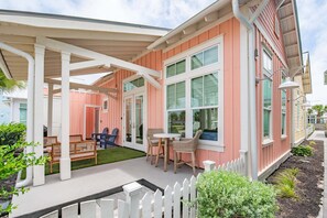 Une maison dotée d’un patio couvert, d’un espace salon extérieur et d’une clôture blanche en bois.
