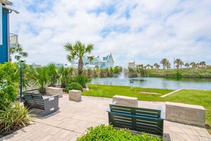 A waterfront property with a large house, a pond with a fountain, and outdoor seating. - Pet Friendly, Resort Pools, Golf Cart Boardwalk to Beach (Port Aransas)