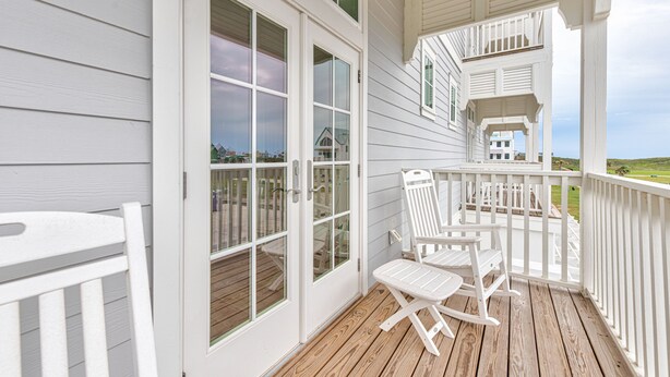 A covered porch with white railings, a wooden deck, and a view of the ocean. - Rooftop Balcony, Boardwalk to Beach, Resort Pool (Port Aransas)