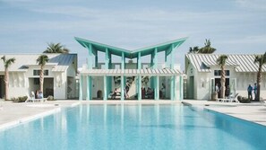 Relax by the rectangular pool surrounded by a white deck and palm trees.