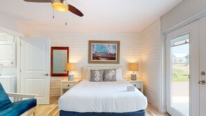 Ein Schlafzimmer mit einem Bett, einem Sessel, einem Bild und einer Tür.