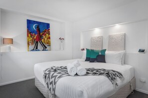 Relax in a stylish space with a large bed, bedside table, and artwork.