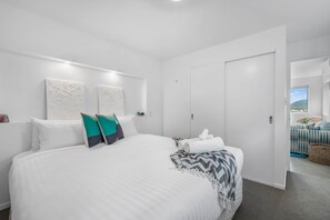 A modern hotel room with a large bed, a wardrobe, and a view of the outdoors.