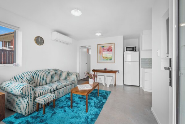 A modern living room with a patterned sofa, a wooden coffee table, and a blue rug.