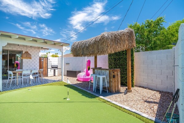 En baghave med putting green, en tiki bar og en bindingsværksbygning.