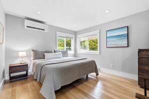 A bedroom with a bed, a nightstand, a lamp, a window, and a painting on the wall. - Unwind in Lakeside Luxury:Private House,Dock,Views, Kayaks - Auburn/Skaneateles (Auburn)