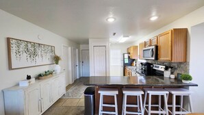 A modern kitchen with white cabinets, a granite countertop, and a stainless steel refrigerator.