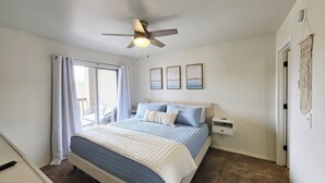 A bedroom with a bed, a ceiling fan, a nightstand, and a door with a macrame curtain.