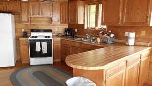 Une cuisine avec des meubles de rangement en bois, une cuisinière, un évier et une poubelle.