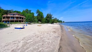 Une plage avec un bâtiment en bois, des chaises longues et des canoës.