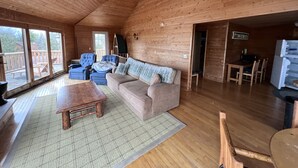 L’intérieur d’un chalet en bois comprend un canapé, des fauteuils, une table basse et un coin repas.