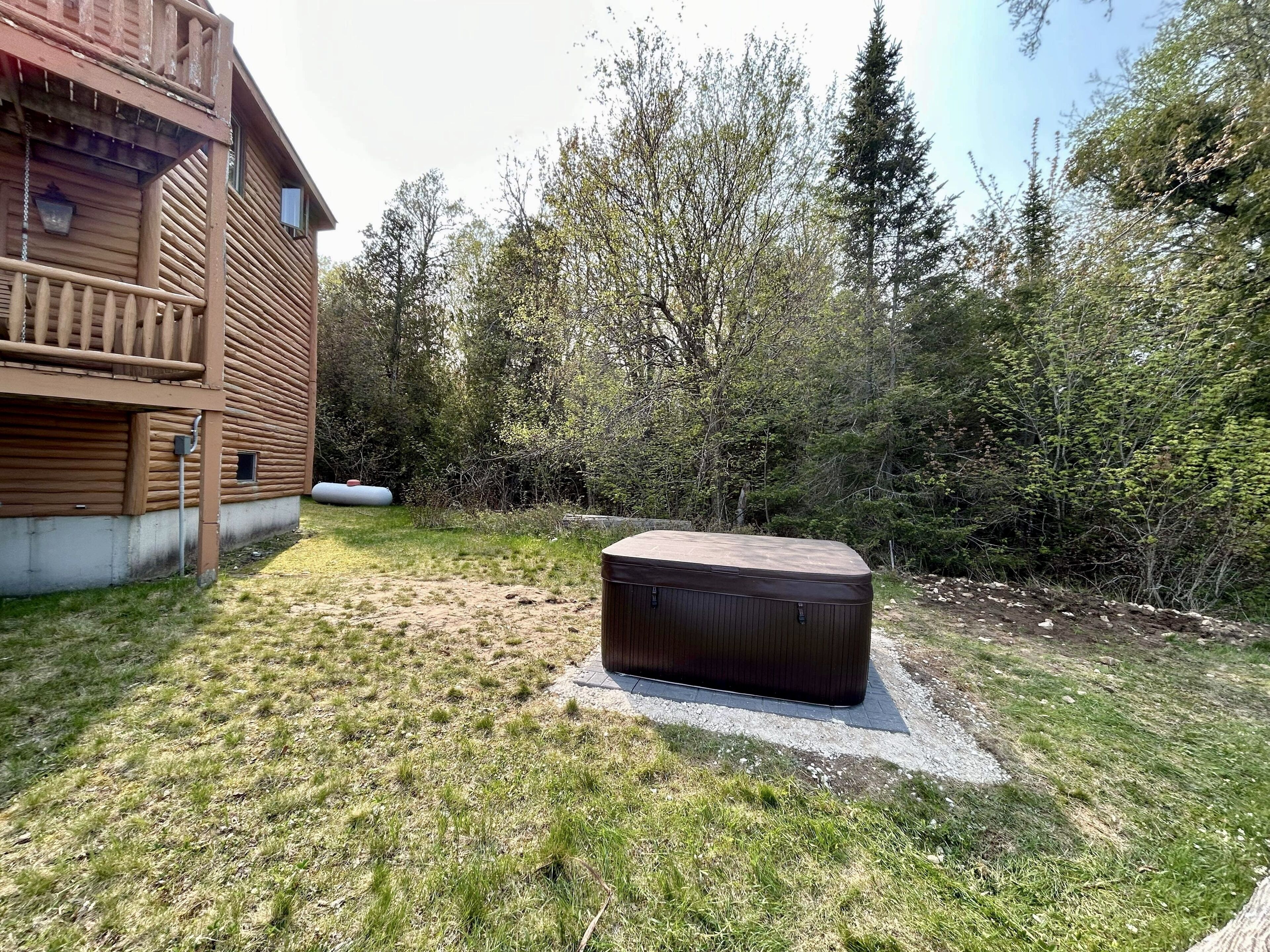 Een houten chalet met balkon, omringd door dicht bos.