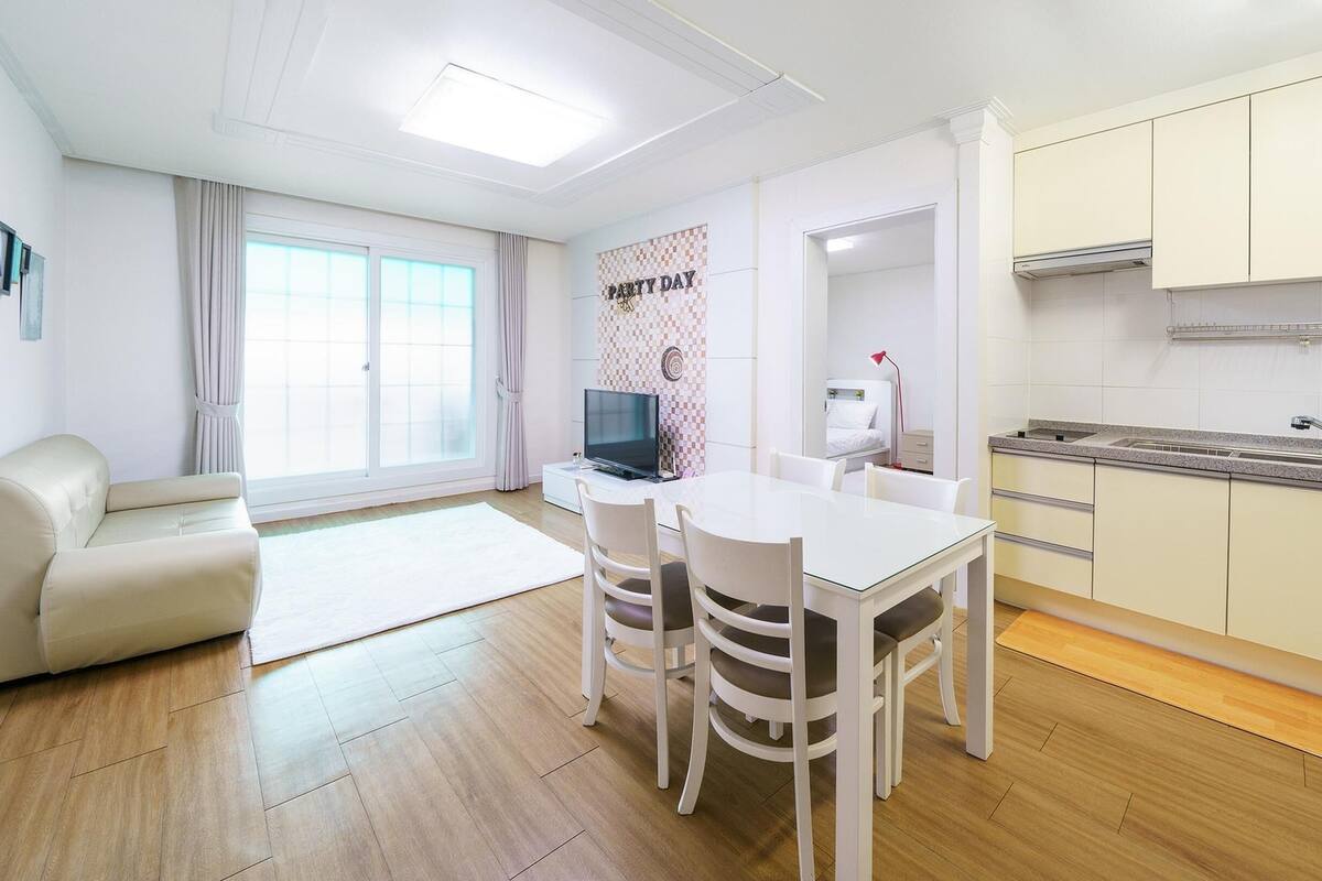 A modern apartment with a dining area, a kitchenette, and a living room.