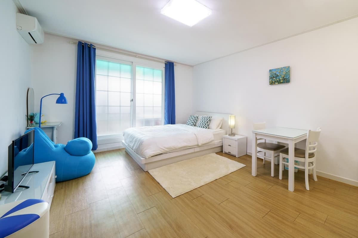 A modern bedroom with a bed, bedside table, and a desk with a chair.