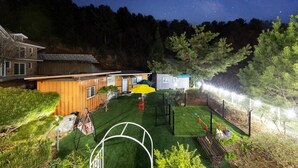 A backyard with a basketball court, a wooden deck, and a small shed. - Gapyeong Oneul-yeogipension (Gapyeong)