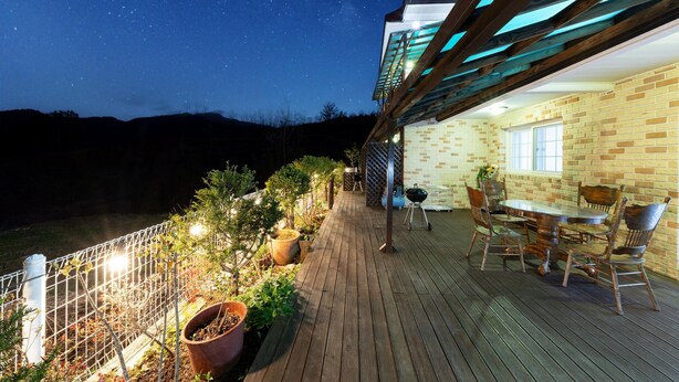 A wooden deck with a brick wall, a table with chairs, and a grill. - Gapyeong Oneul-yeogipension (Gapyeong)