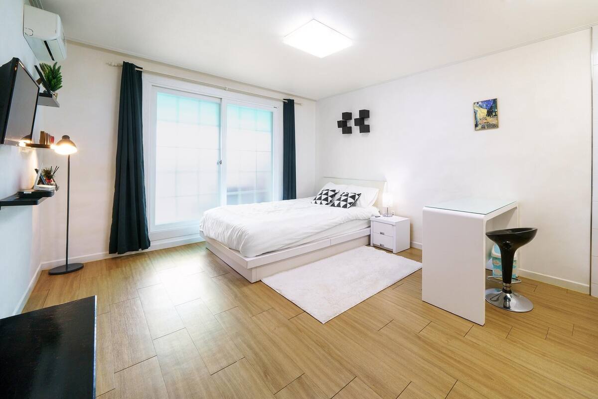 A modern bedroom with a bed, bedside table, and a small desk with a chair.