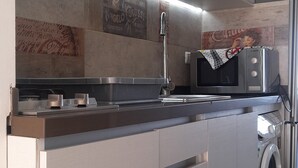Une cuisine moderne équipée d’appareils électroménagers en acier inoxydable, d’un four encastré et d’un four à micro-ondes.