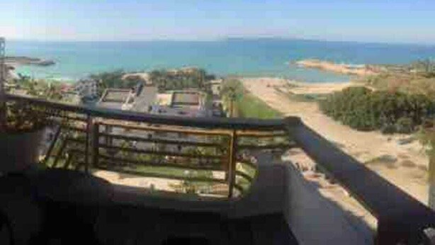 Un balcon avec vue sur la mer et une plage de sable.