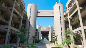 Un edifici d'àmbit elevat amb un atrium central, balcons amb vegetació i palmeres al pati.