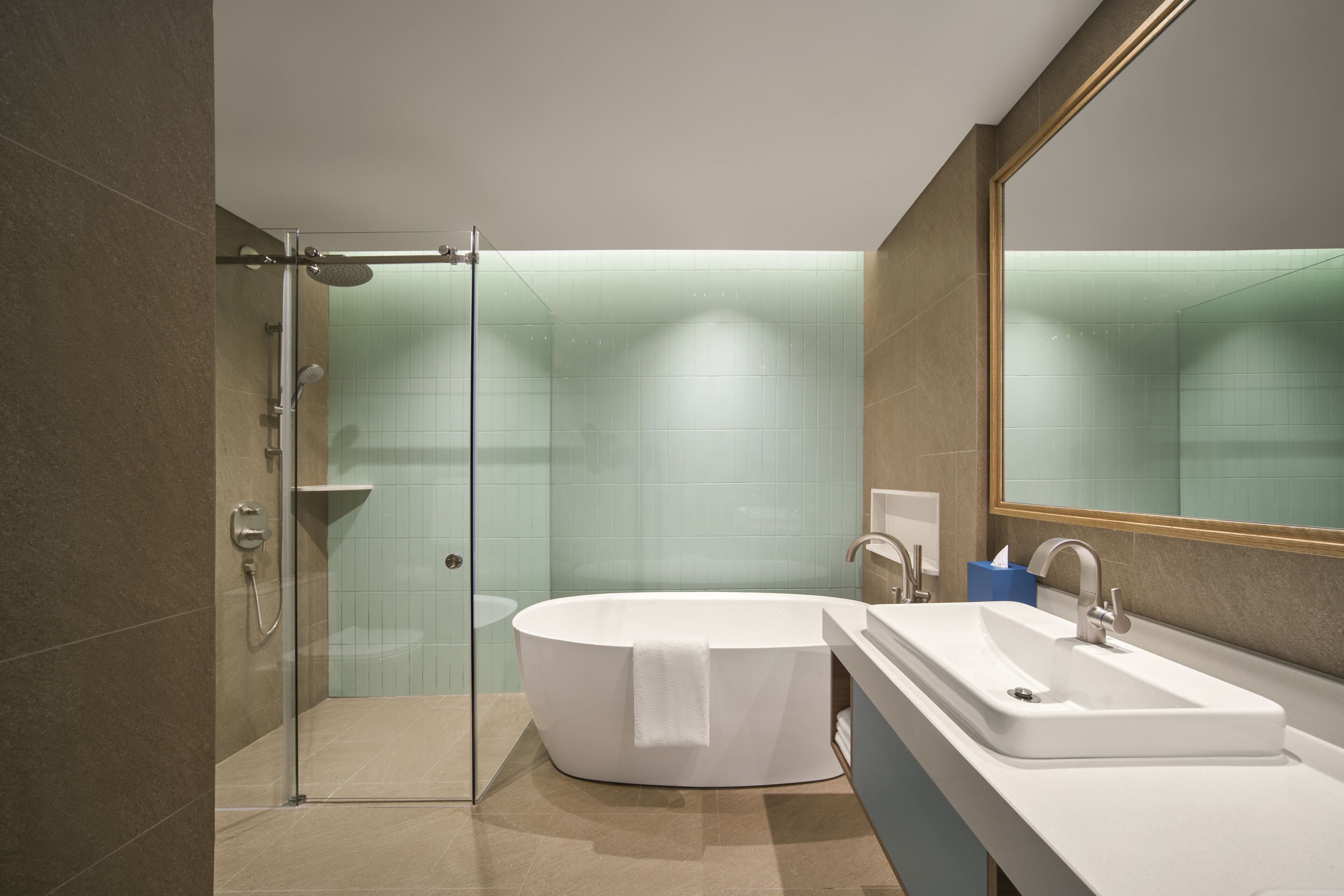 A modern bathroom with a glass-enclosed shower, a freestanding bathtub, and a large mirror.