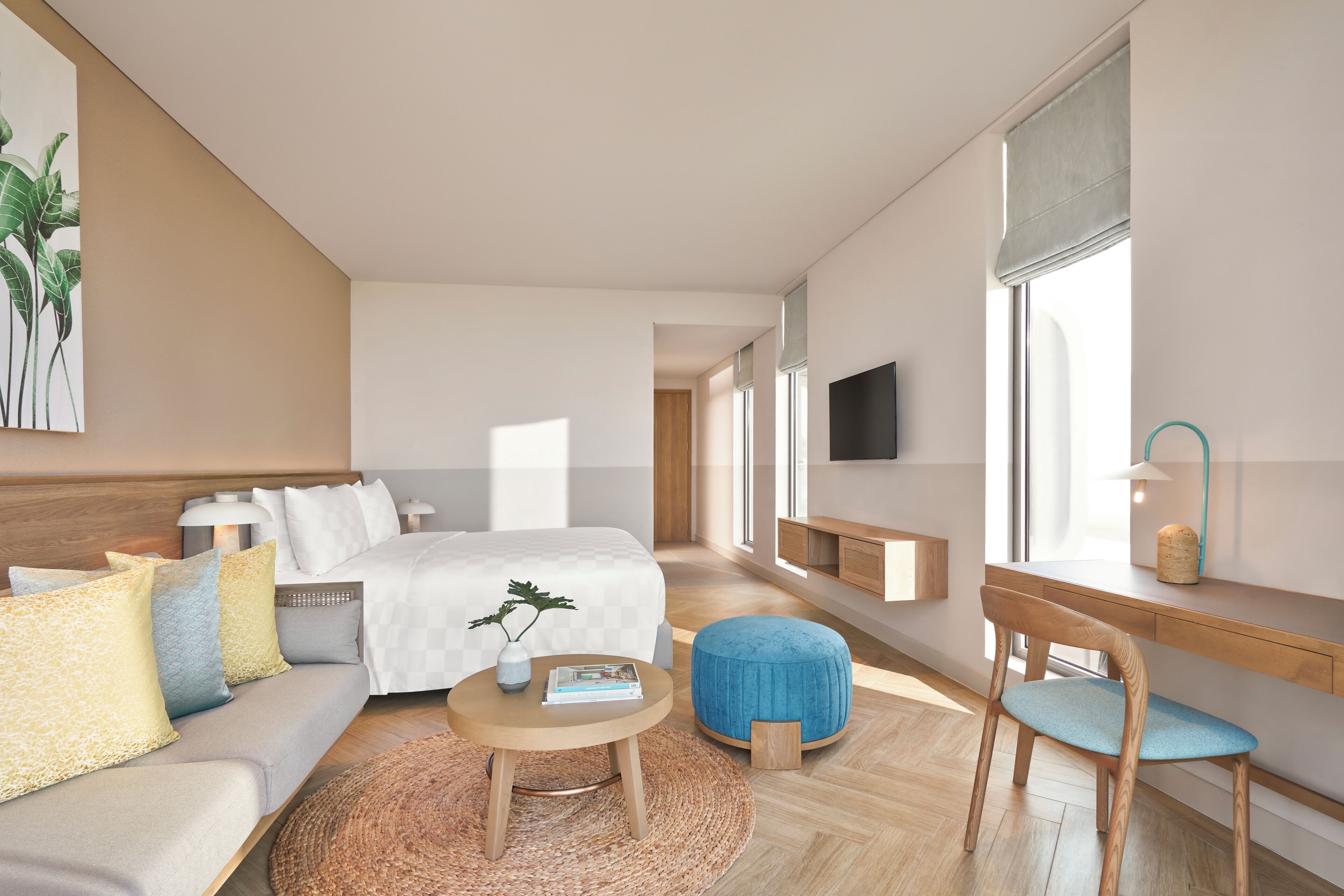 Una habitación de hotel moderna con cama, sofá, una mesita redonda, una silla, televisión y ventana con vistas.