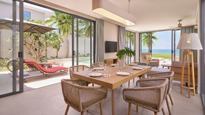 A modern dining area with a large table, wicker chairs, and a view of the ocean. - IXORA Ho Tram By Fusion (Ho Chi Minh City)