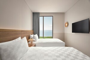 A hotel room with two beds, a large window with a view of the sea, a flat-screen TV, and a wooden headboard.