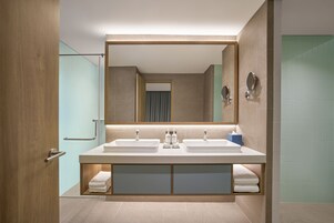 A modern bathroom with a double sink, a large mirror, and a glass shower enclosure.