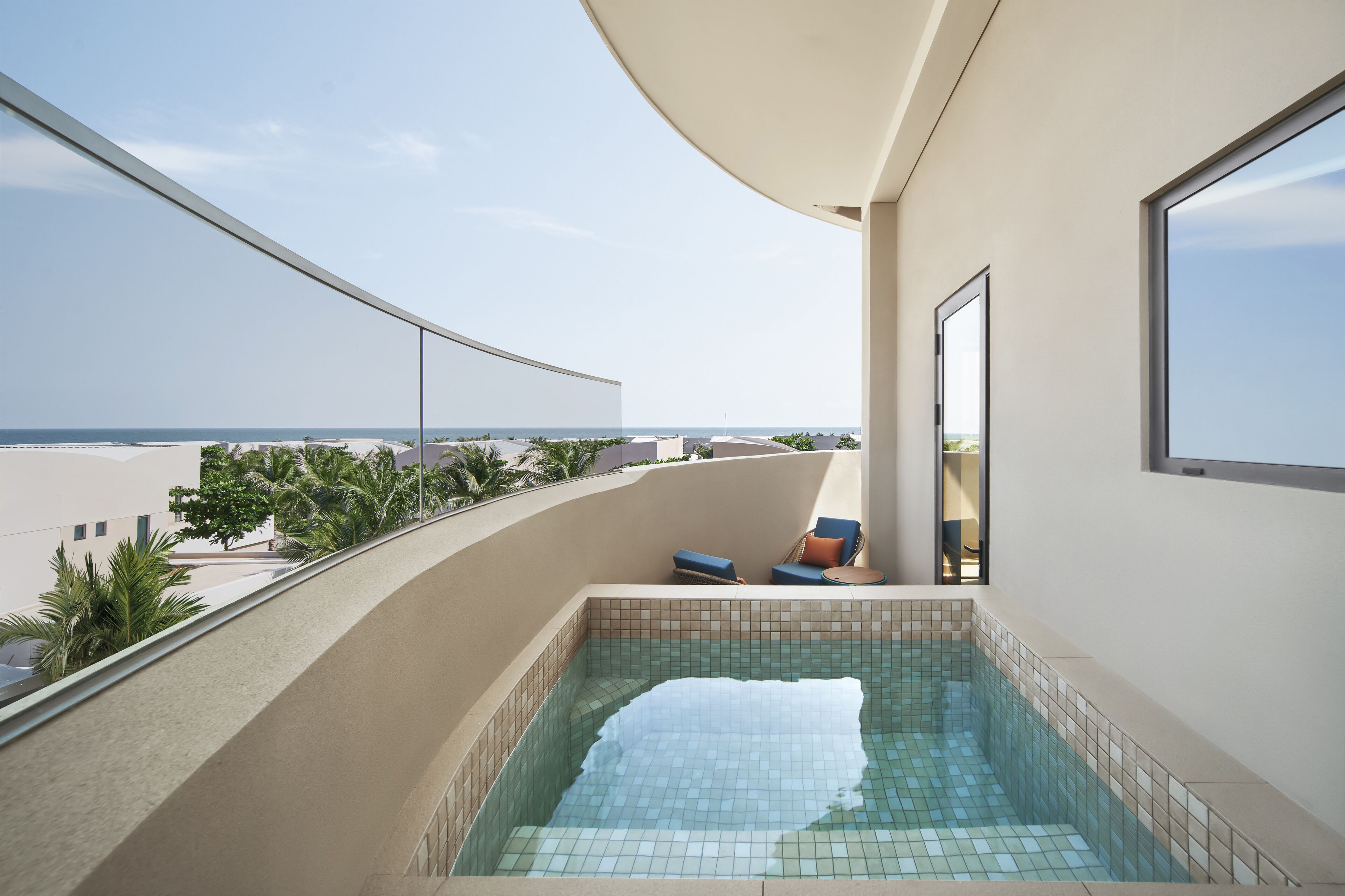 Un balcón con una piscina pequeña, vistas al mar y un área de descanso con cojines.