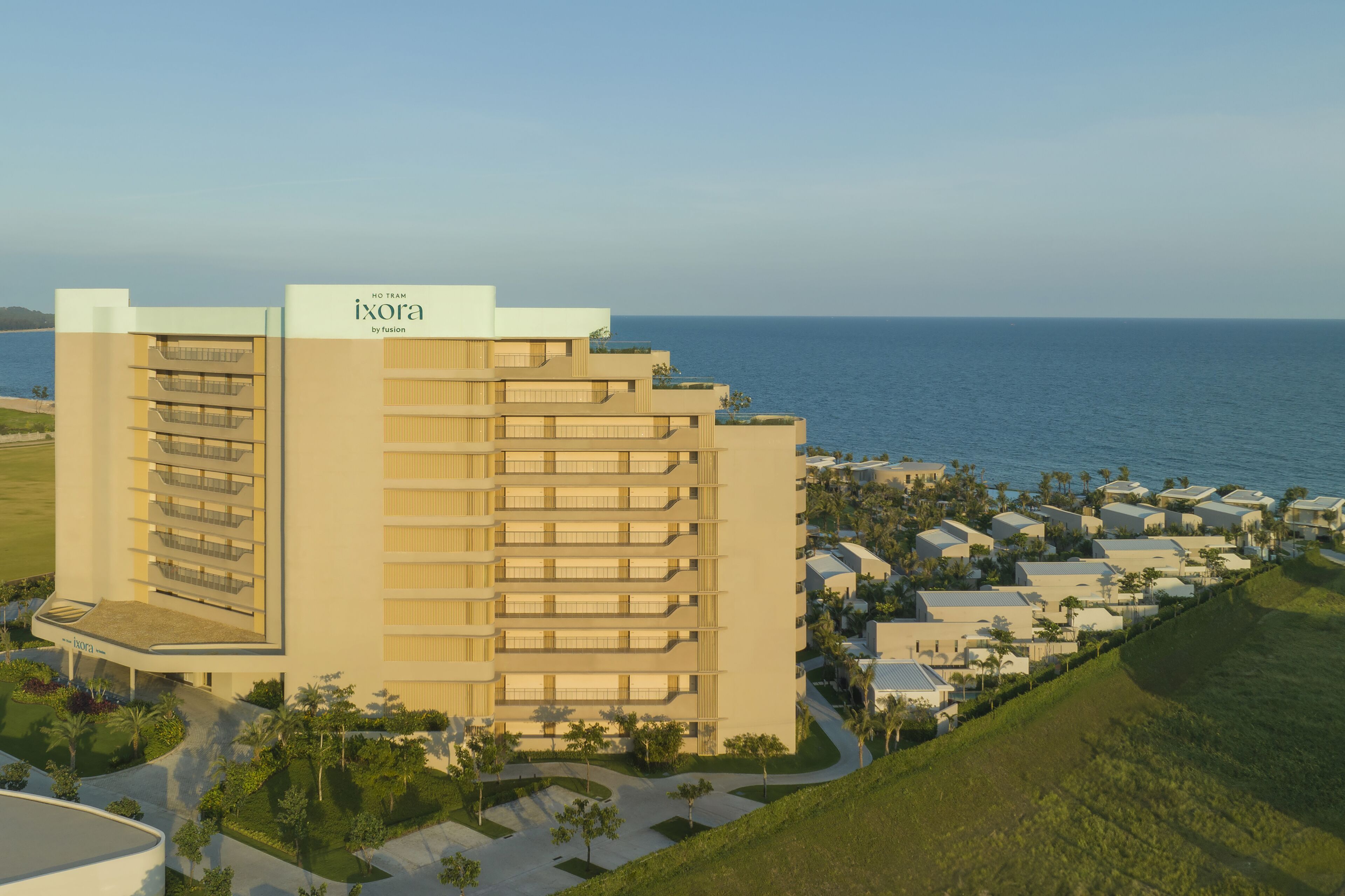 A high-rise hotel with multiple balconies and a view of the ocean.
