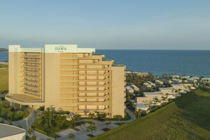 A high-rise hotel with multiple balconies and a view of the ocean.