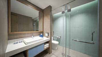 A modern bathroom with a glass-enclosed shower, a large mirror, and a white sink.