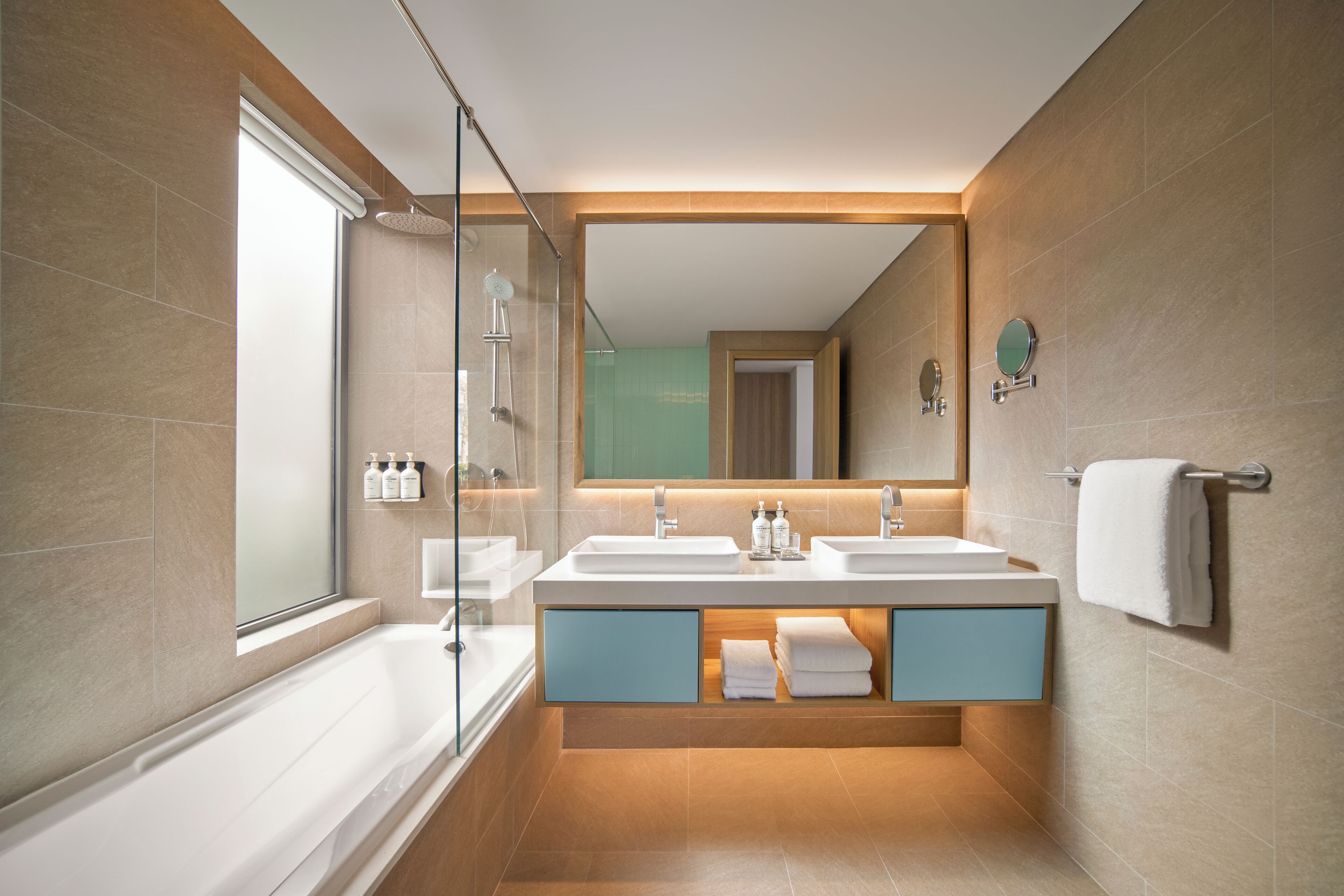 A modern bathroom with a glass shower enclosure, dual sinks, and a vanity with storage.