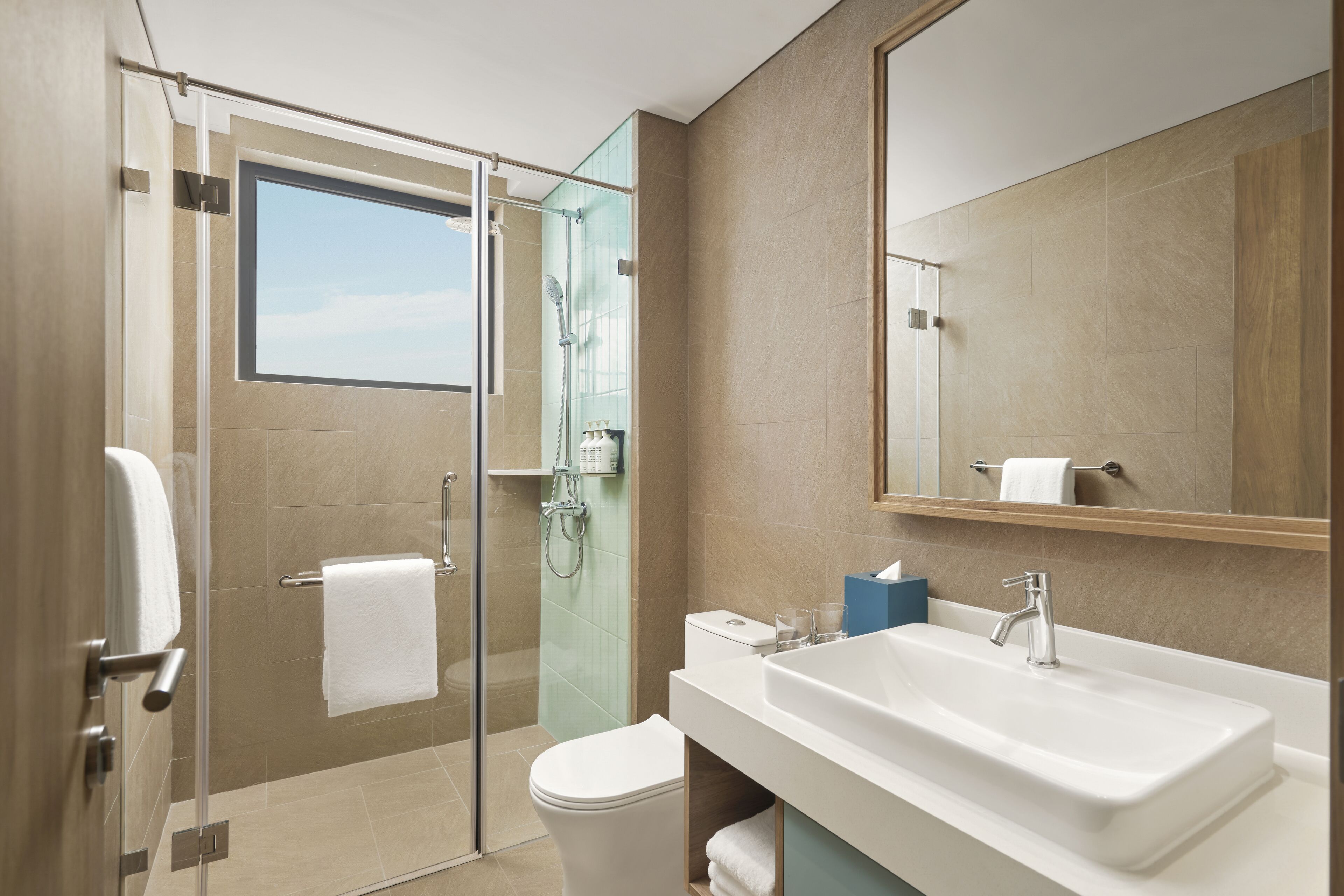 A modern bathroom with a glass shower enclosure, a white sink, and a large mirror.