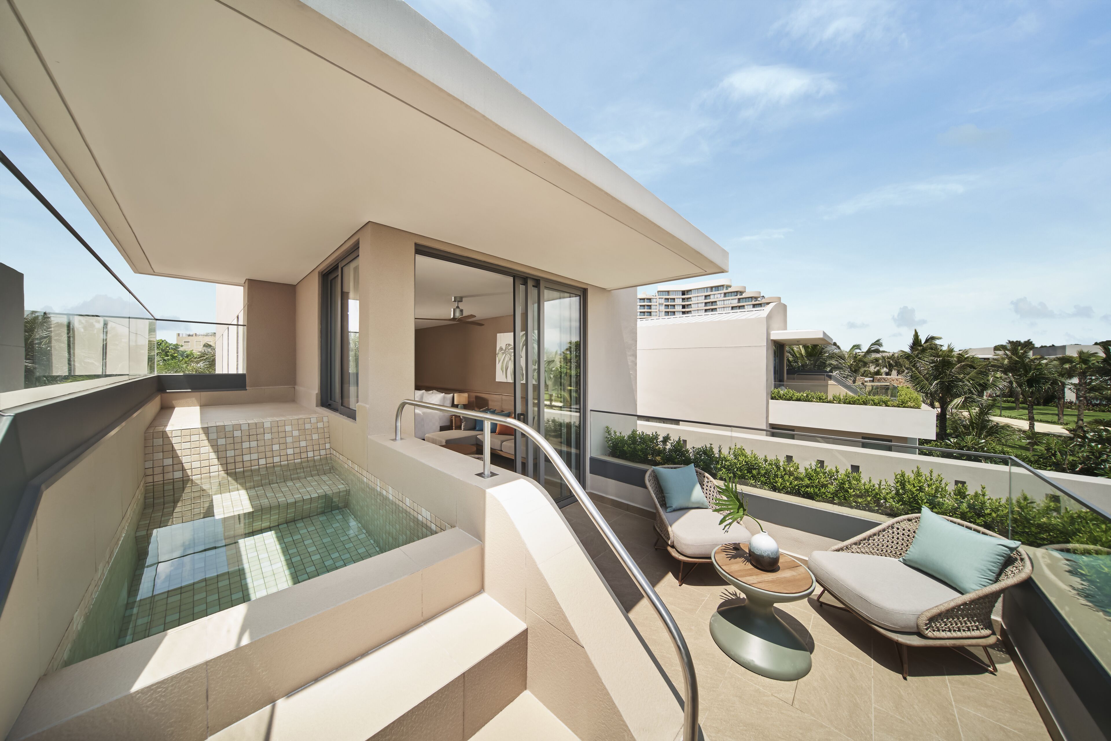 Un balcón moderno con piscina cubierta de vidrio, mobiliario de exterior y vistas de los edificios circundantes.