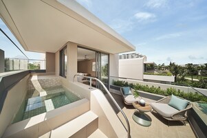Un balcón moderno con piscina cubierta de vidrio, mobiliario de exterior y vistas de los edificios circundantes.