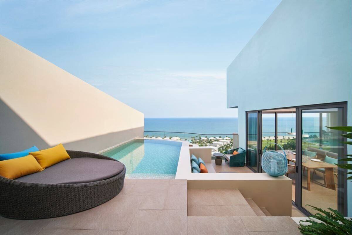A modern outdoor balcony with a pool, seating area, and a view of the ocean.