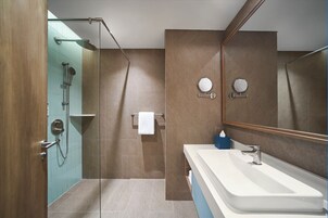 A modern bathroom with a glass-enclosed shower, a large mirror, and a white sink.